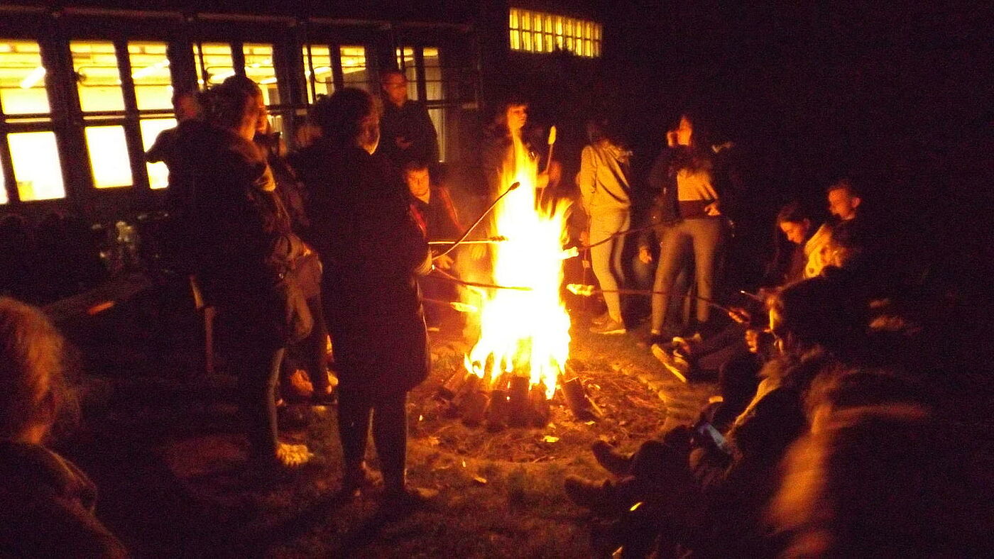 Eine Gruppe Schüler macht Stockbrot am Lagerfeuer.