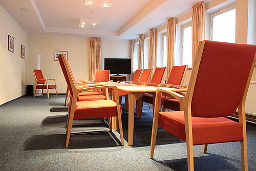 Rote Stühle im Clubraum des Gästehaus Angeln.