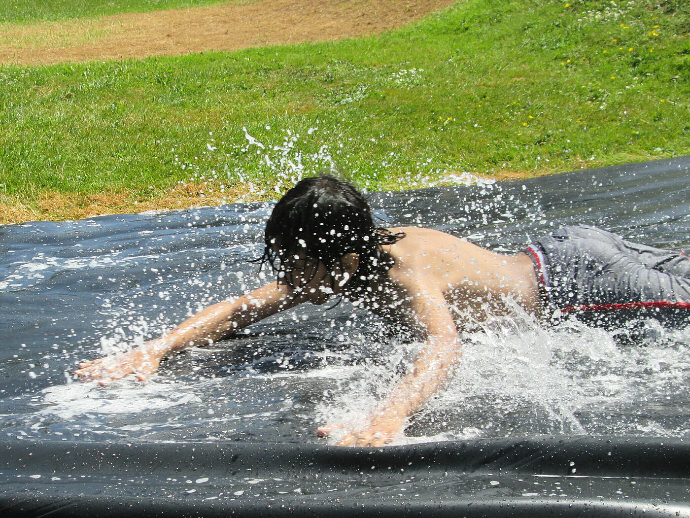 Junge schlittert über Wasserrutsche.