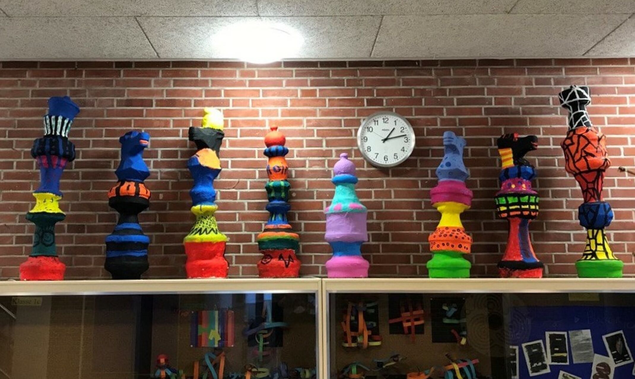 Bunte Figuren vor einer Uhr.