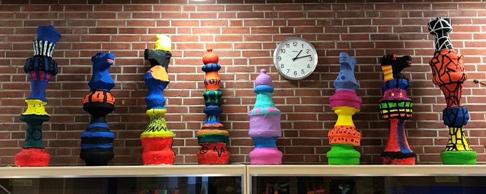 Bunte Figuren vor einer Uhr.